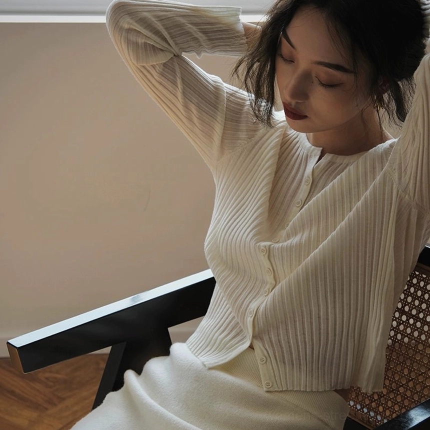 Cream white ribbed knit button-up slim fit cardigan for women shown in relaxed side pose