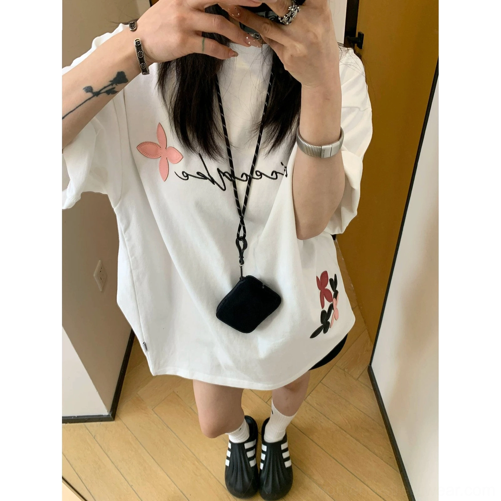 Korean streetwear inspired oversized cotton T-shirt with flowing script lettering, scattered floral motifs, and a loose unisex-style silhouette