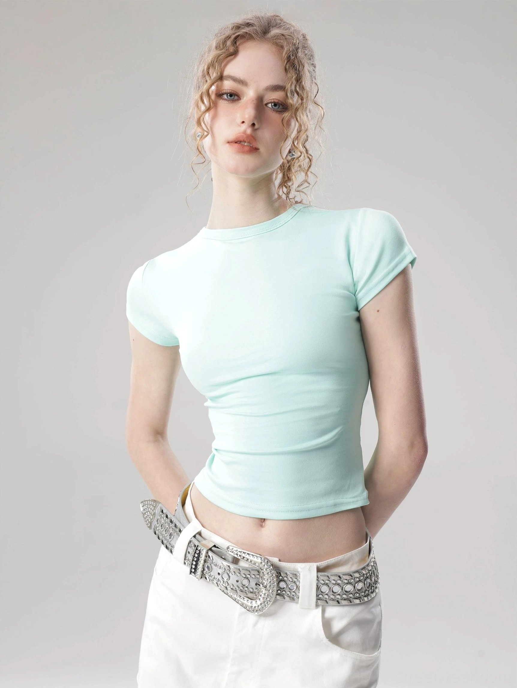 Mint green solid color flutter sleeve cropped top with fitted crew neck silhouette shown in a minimalist studio close-up