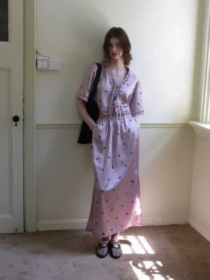 Lavender floral embroidered satin two piece outfit with ruffle trim blouse and flowing long skirt styled with black tote bag