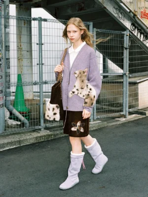 Lavender fuzzy cat knit cardigan worn in an urban streetwear outfit with spotted cat applique, brown mini skirt, purple fuzzy boots, and furry tote bag