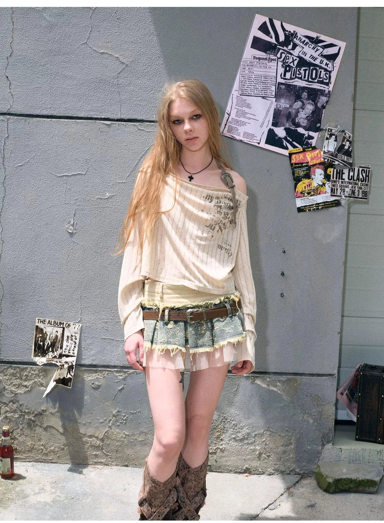 Layered blue denim mini skirt with reconstructed workwear styling, distressed edges, brown leather belt, and translucent mesh hem