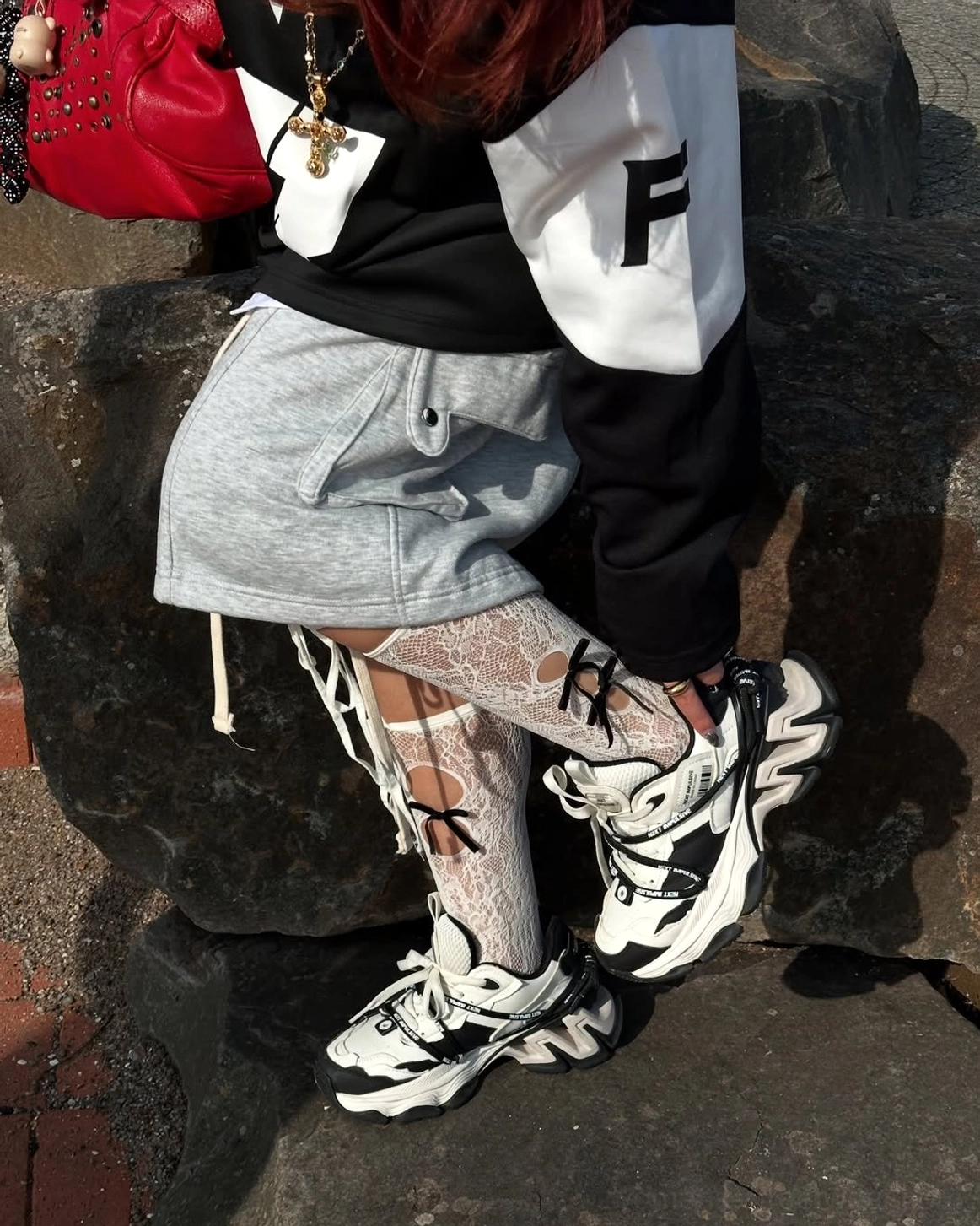 Layered chunky dad sneakers styled with lace socks in an outdoor streetwear outfit