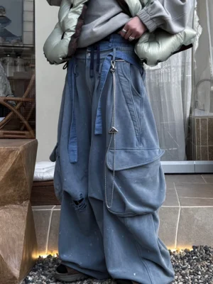 Layered waist washed blue cargo wide leg pants styled with a puffer jacket in a modern streetwear setting