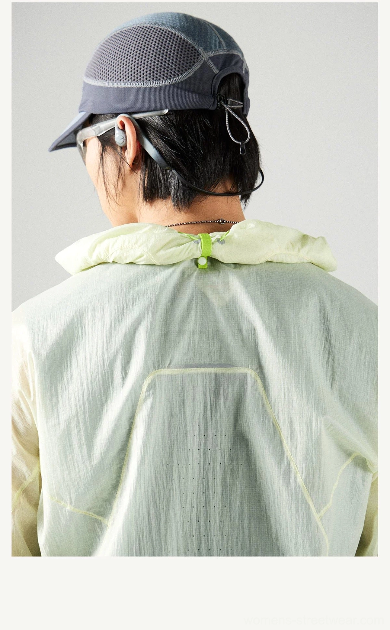 Rear close-up of the Lemon Green UV protection jacket with hood down, reflective contrast stitching, hood toggle, and crinkled outdoor fabric