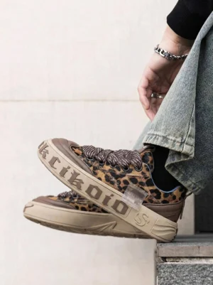Leopard print chunky skate sneakers worn with jeans in a casual streetwear outfit on stone steps