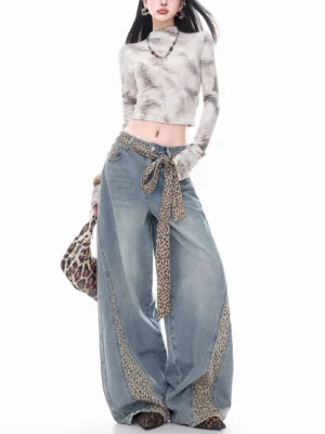 Front view of women's washed blue leopard panel curve-leg wide jeans with matching waist sash in a streetwear outfit