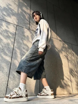 Model wearing leopard print deconstructed platform canvas sneakers with an oversized graphic sweatshirt, cropped wide-leg denim, white socks, and headphones in a Seoul-inspired streetwear outfit