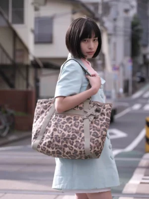 Large leopard print commuter tote bag with sage green straps styled by model on an urban street