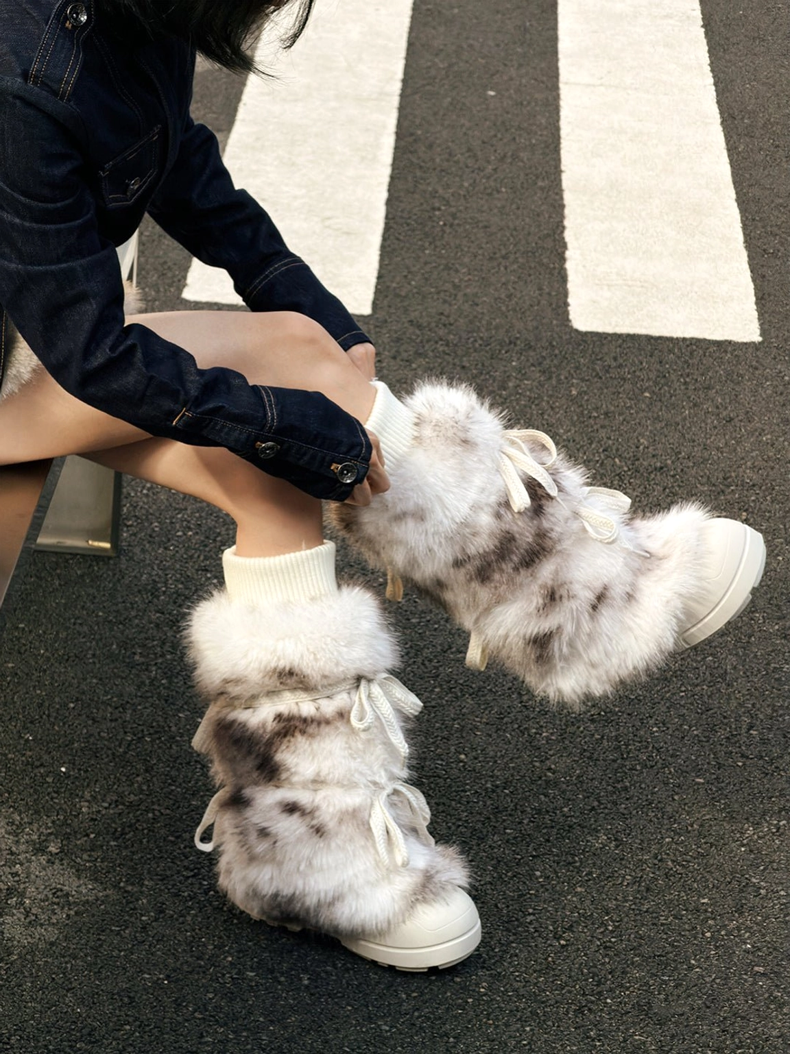 Model putting on leopard print fuzzy platform boots with lace-up side details on an urban street