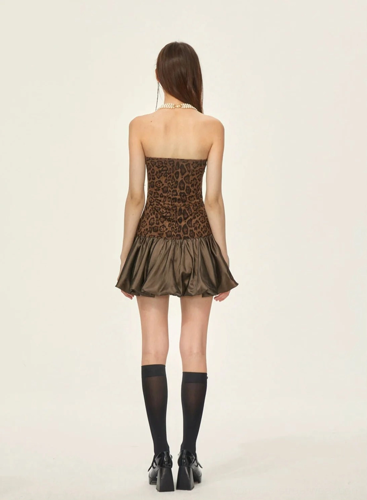 Back view of leopard print strapless bubble hem mini dress styled with rhinestone knee-high socks and black loafers