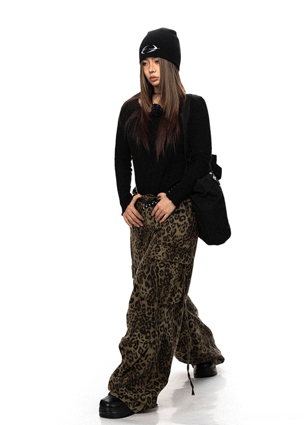 Front walking view of leopard print wide leg cargo pants styled with a black beanie and relaxed urban streetwear outfit