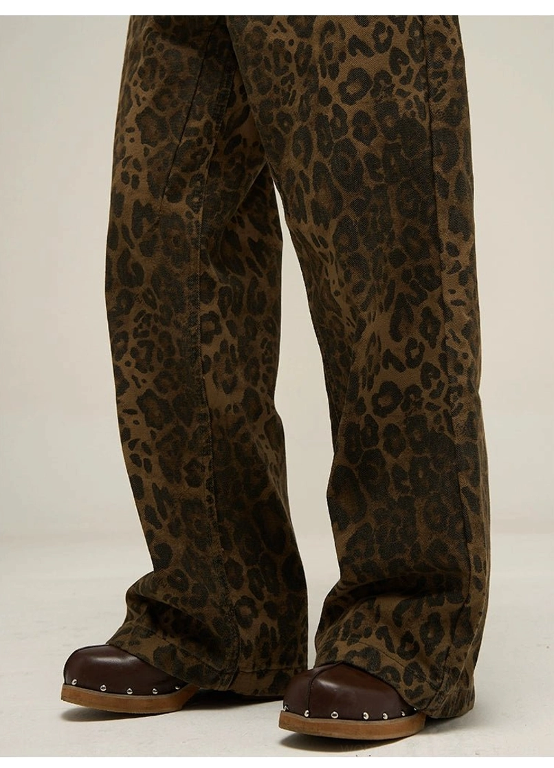 Close-up of the wide straight-leg opening on brown and black leopard print denim-style streetwear pants worn with leather clogs