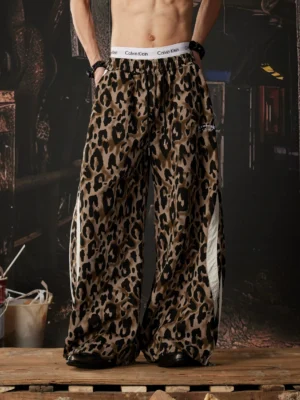 Front full body view of brown leopard print wide leg track pants with white side stripes in an industrial streetwear setting