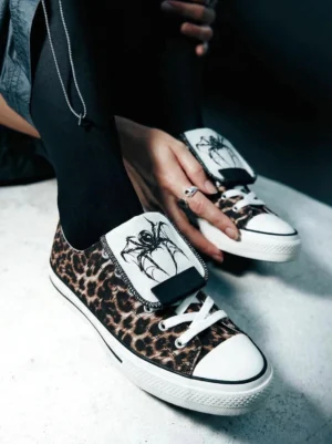 Leopard print spider-tongue canvas sneakers worn with black tights showing white laces and white rubber toe caps