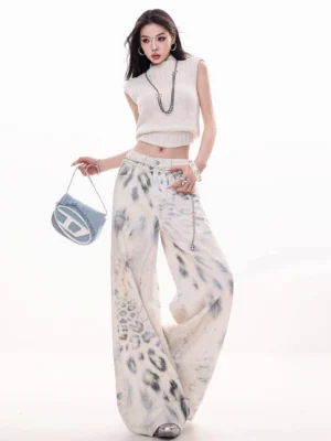 Three-quarter view of relaxed leopard print tie-dye wide-leg jeans with natural waist, flowing denim drape, and visible waist chain styling