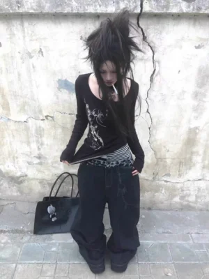 Front low angle view of black leopard waistband chain baggy jeans styled on a punk streetwear model against a weathered concrete wall