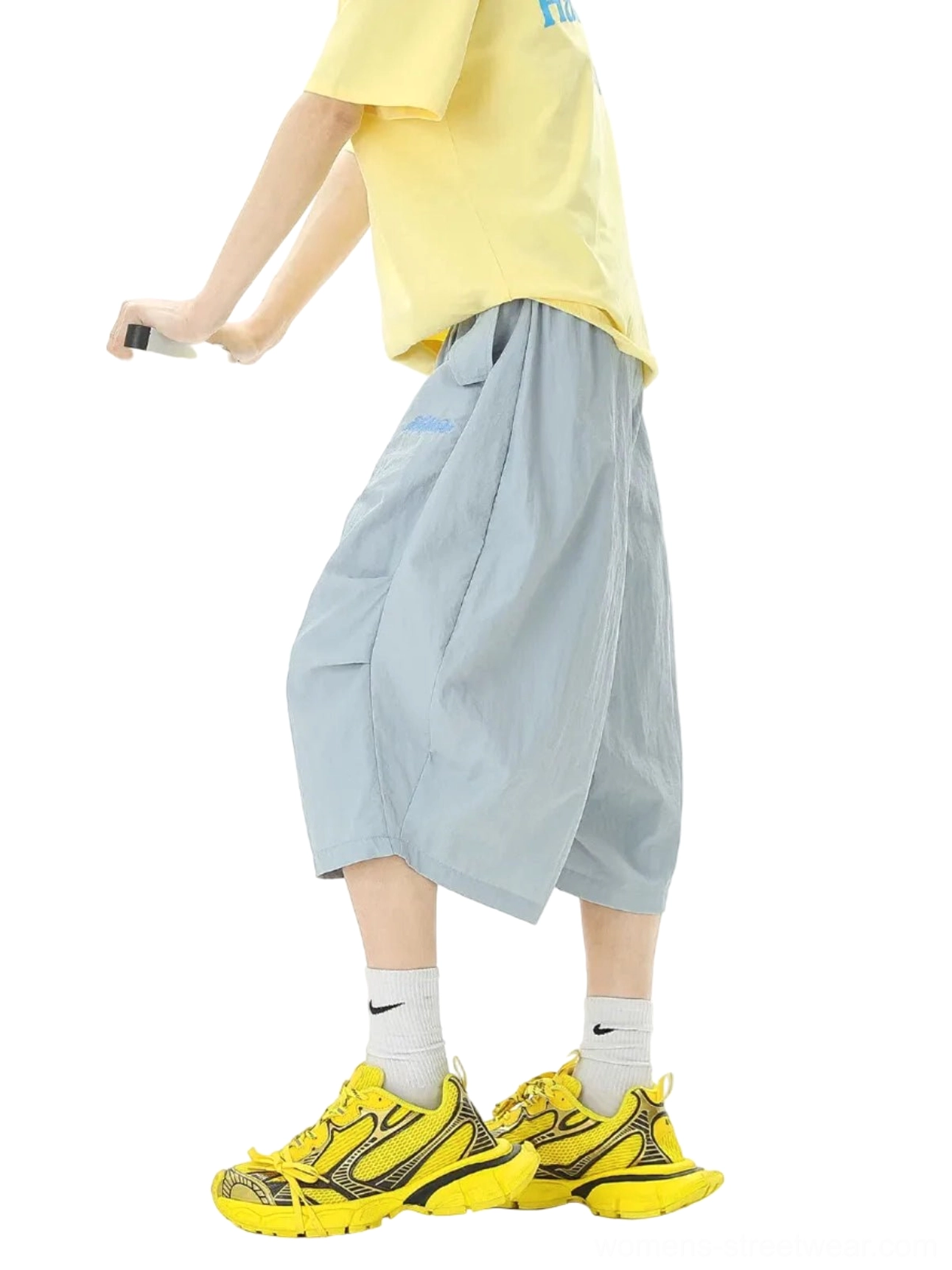Side view of light ash blue oversized balloon jogger shorts showing the three-dimensional pleated silhouette, cropped mid-calf length, and relaxed streetwear fit