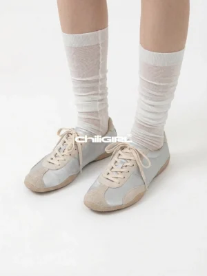 Light beige retro lace-up sneakers styled with sheer white pleated mid-calf socks in a clean studio close-up showing the low-top silhouette