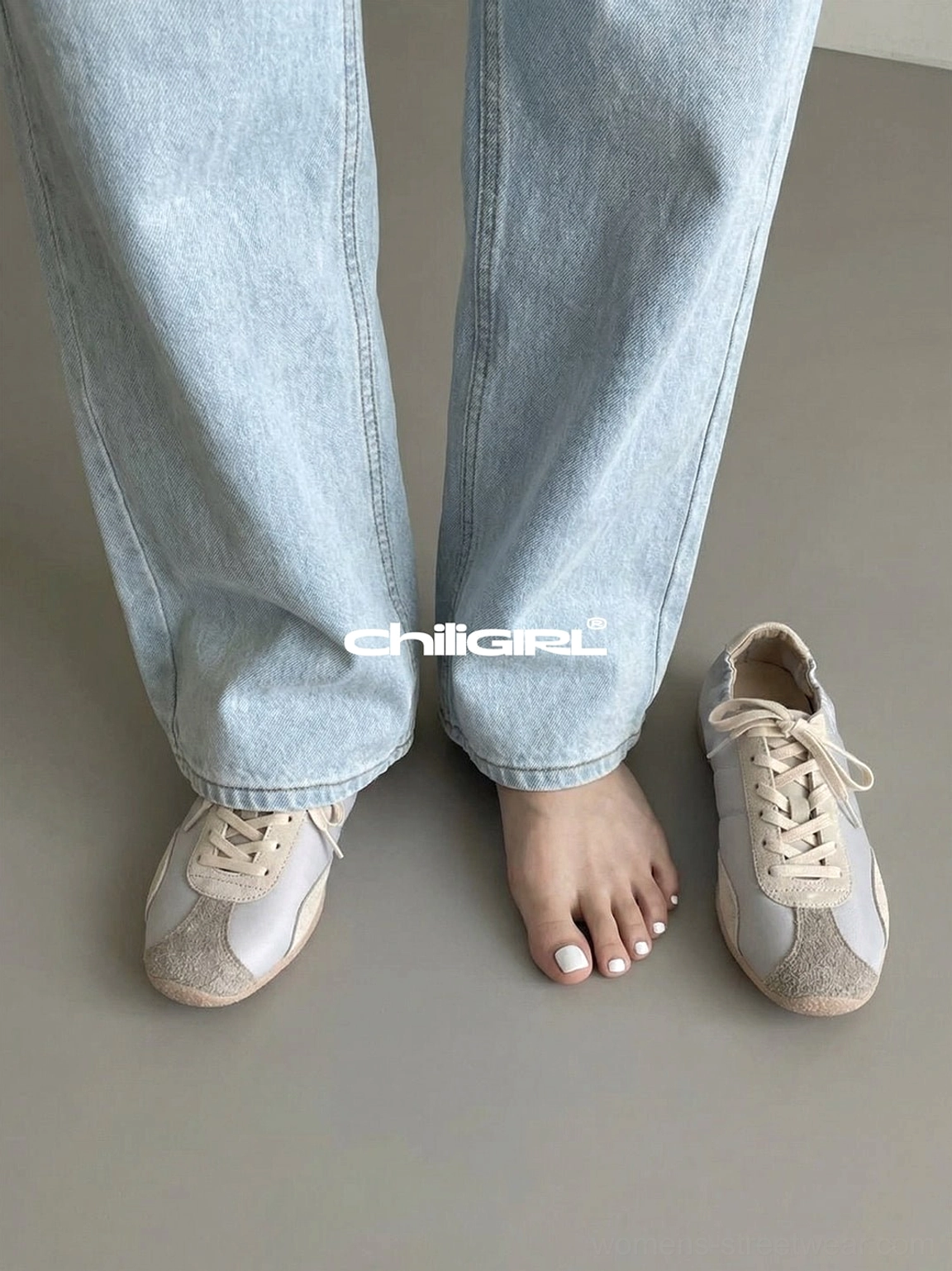 Front view of light beige retro lace-up trainers paired with light blue wide-leg jeans, highlighting the rounded toe and flat sneaker profile