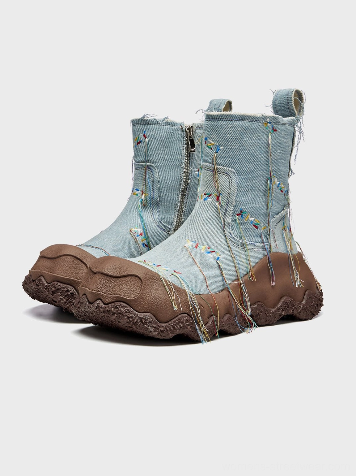 Pair of light blue denim fringe western ankle boots with chunky brown rubber soles in side display