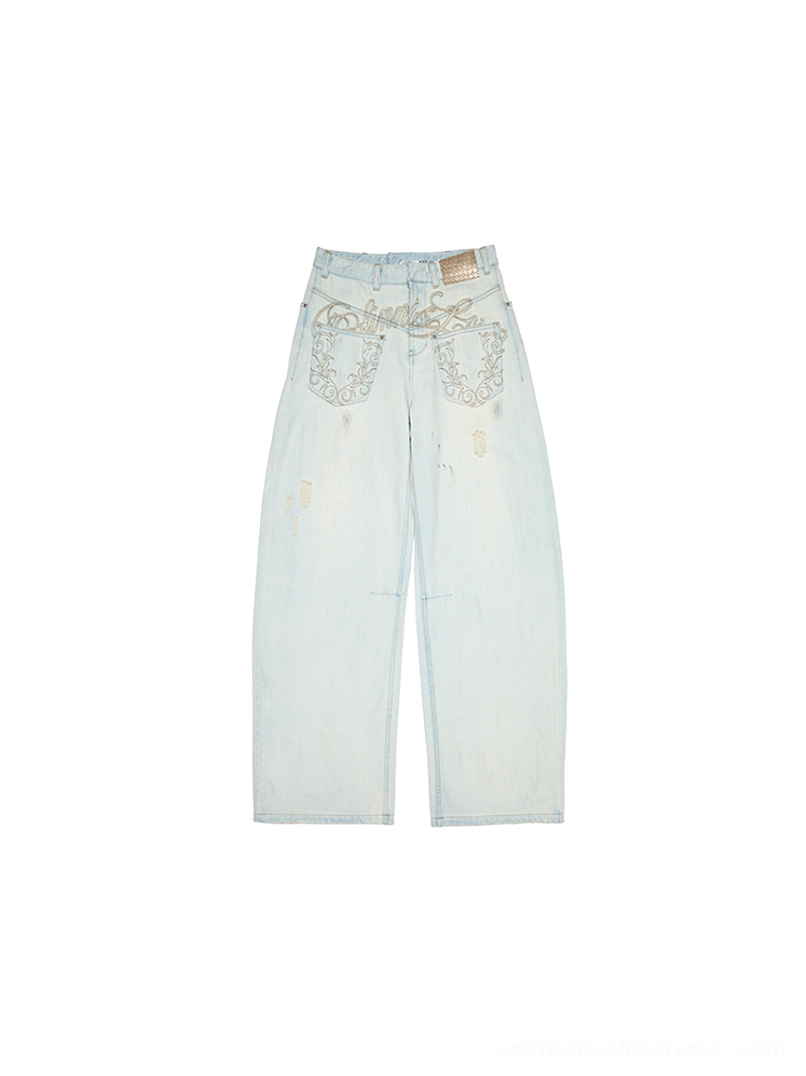Flat lay back view of light blue distressed arc-leg jeans with faded denim, embroidered waistband, and decorative back pockets