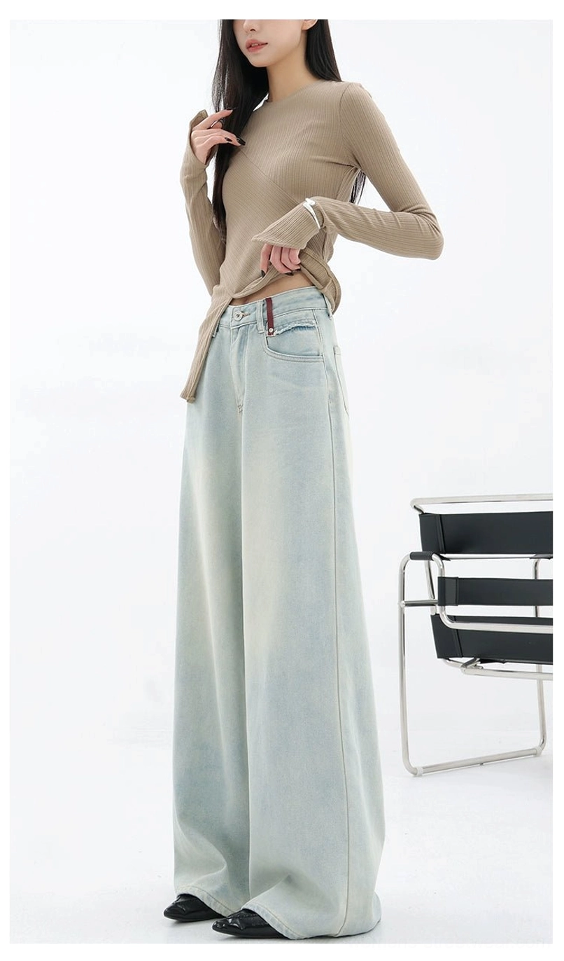 Back three-quarter view showing the loose wide-leg fit and faded texture of light blue embroidered streetwear denim pants