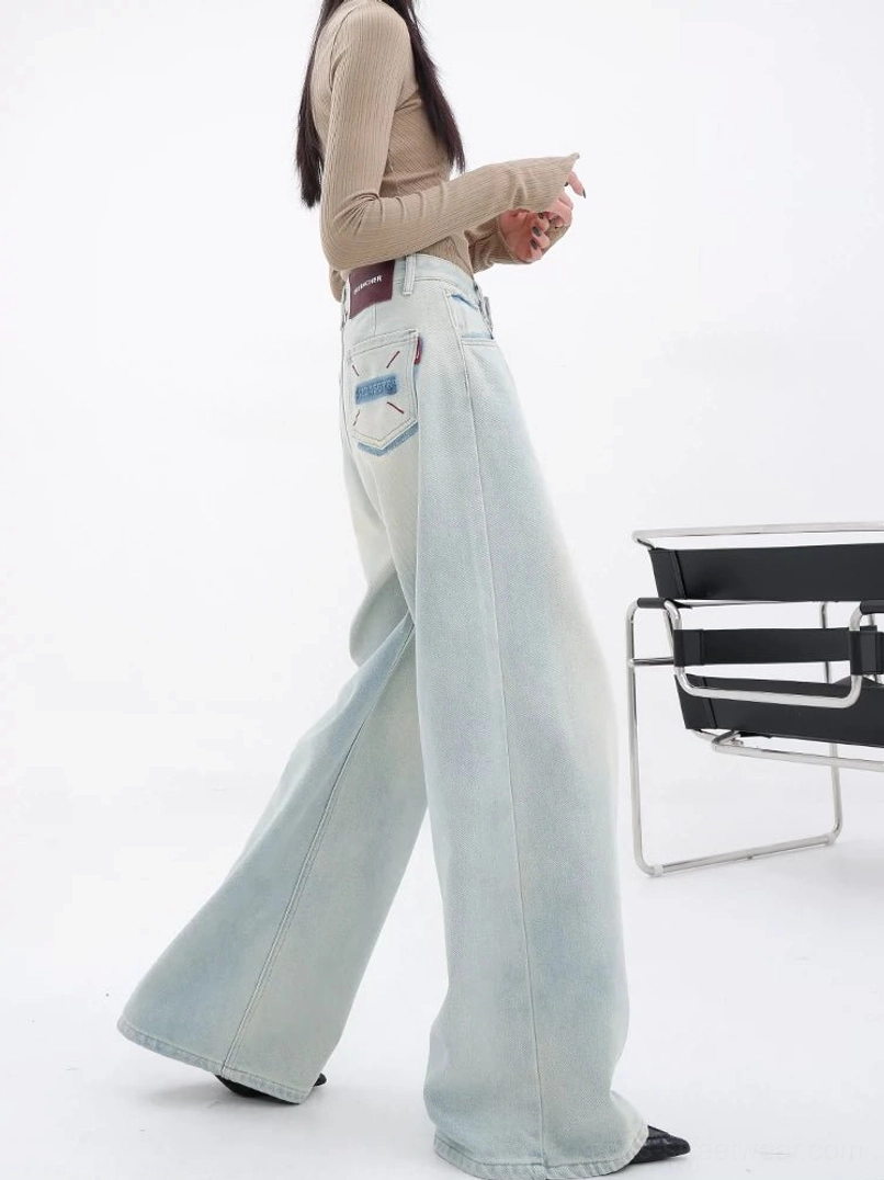 Back three-quarter view of women wearing light blue embroidered wide-leg streetwear jeans with a faded denim wash and detailed back pocket