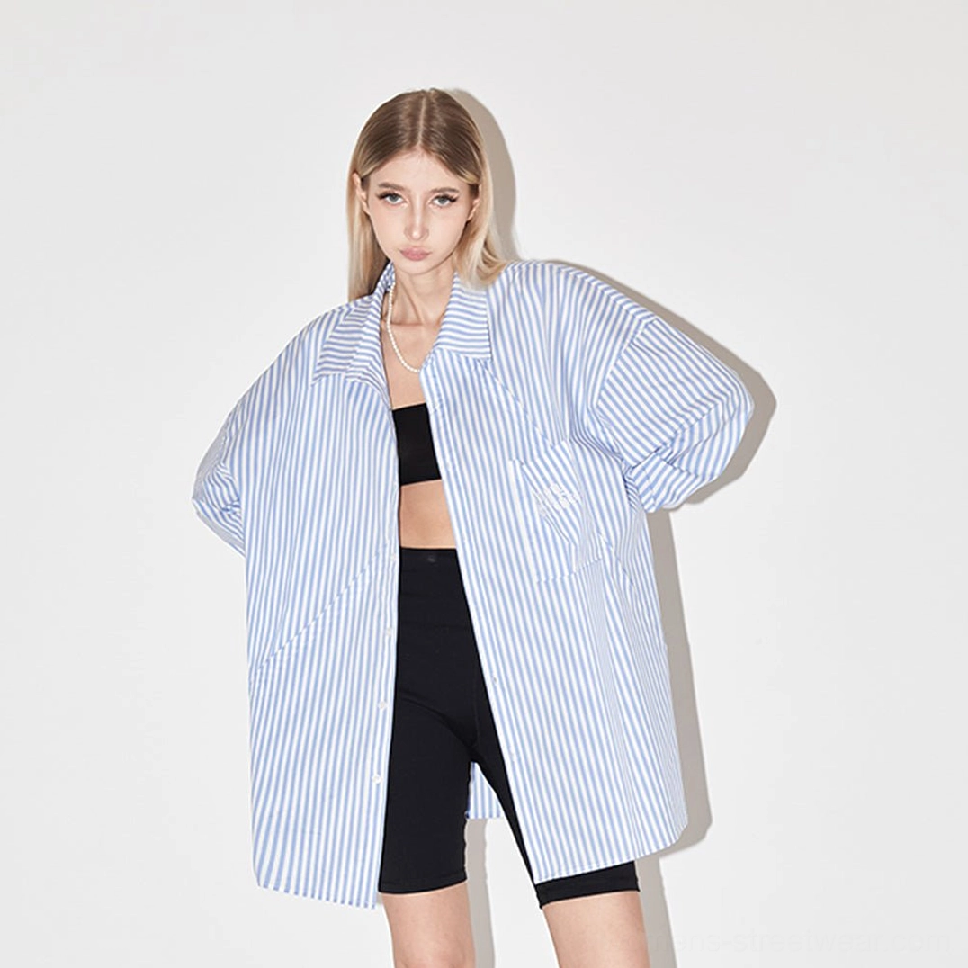 Female model styling light blue geometric panel striped oversized streetwear shirt over crop top and biker shorts