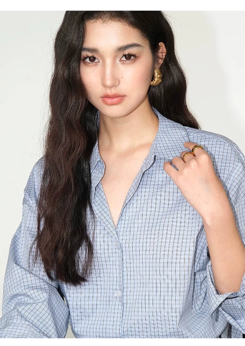 Close-up of light blue gingham cotton blend button-up shirt pointed collar and polished button placket
