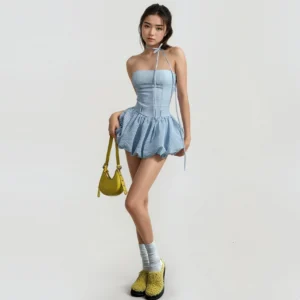 Light blue gingham mini bubble romper dress with halter neckline, corset waist and ruffled hem styled with yellow platform loafers
