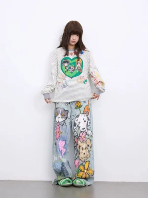 Front view of relaxed light blue streetwear jeans with playful hand-drawn graffiti artwork styled with a striped top and casual flats
