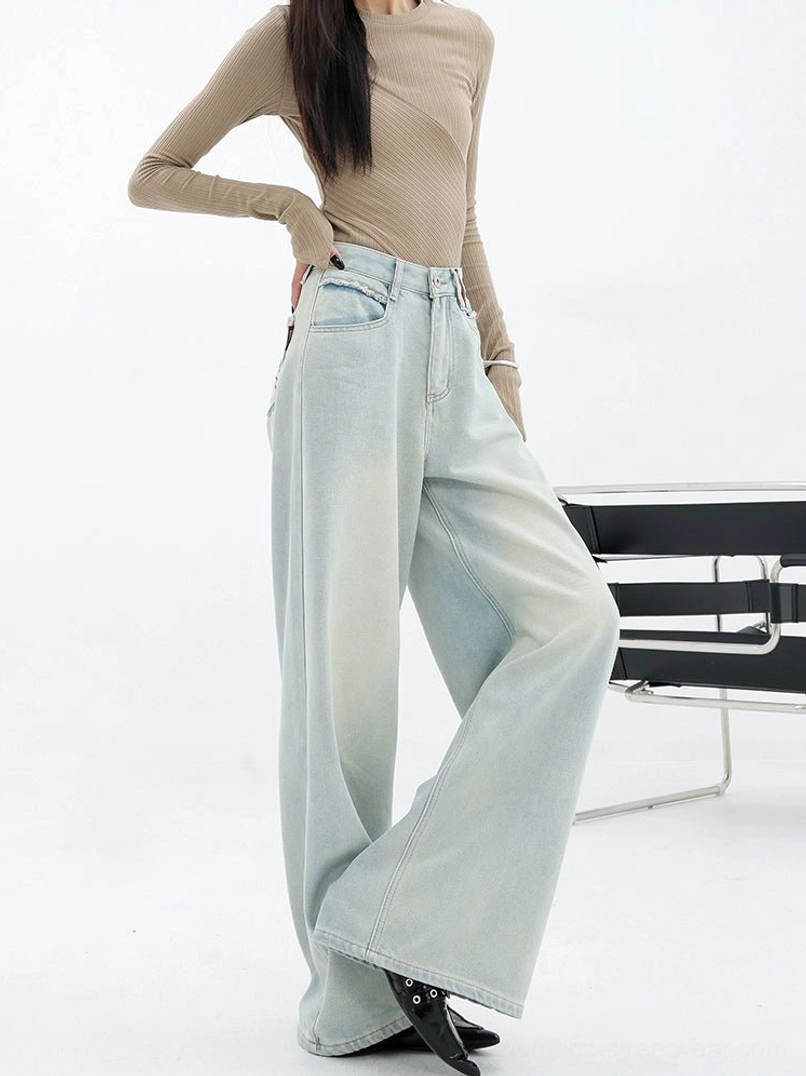 Side three-quarter view of light blue high-rise wide-leg denim jeans styled with a fitted neutral top and black shoes
