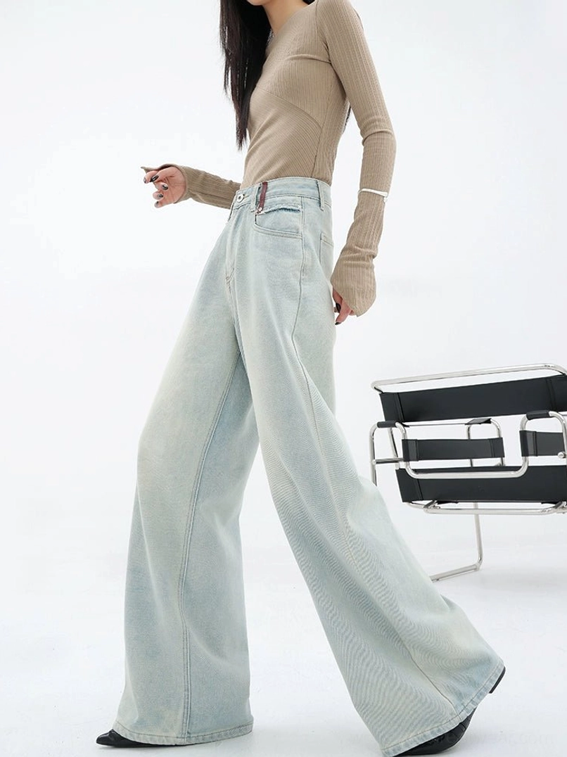 Side walking view of light blue loose straight-leg embroidered denim pants with relaxed streetwear proportions