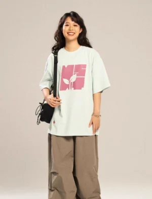 Light blue oversized graphic T-shirt with pink contrast botanical logo, subtle cross embroidery, and relaxed Seoul streetwear silhouette