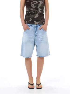 Front view of relaxed light blue denim Bermuda shorts featuring a mid-rise waist, oversized straight-leg fit, and frayed raw hems