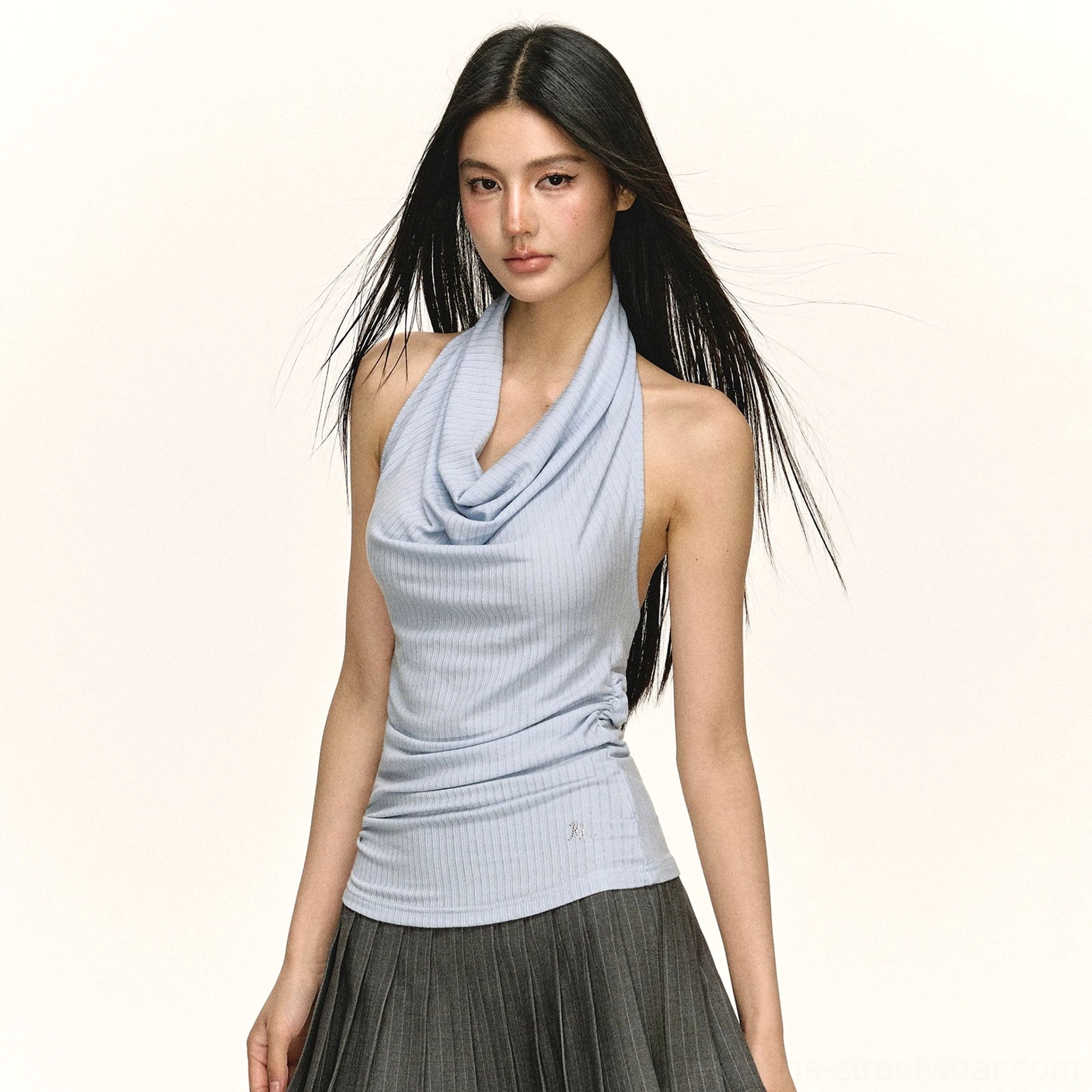 Close up three quarter view of a light blue ribbed draped cowl neck halter top with a slim tailored fit