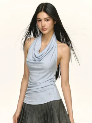 Light blue ribbed draped cowl neck halter top shown from a front three quarter view with a fitted silhouette and grey pleated midi skirt