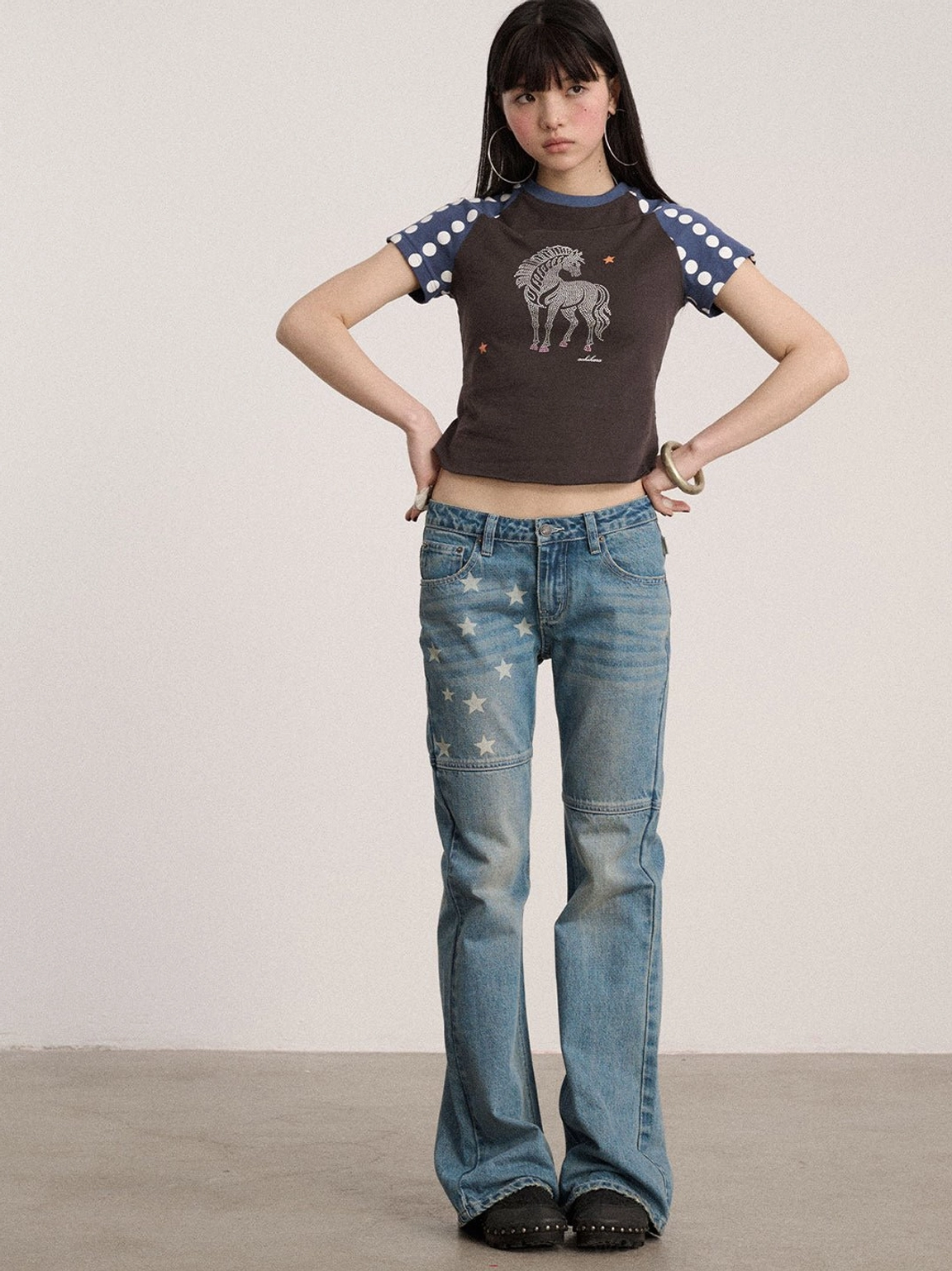 Front view of light blue washed star print flare jeans with classic five-pocket styling, low-rise waist, and flared legs