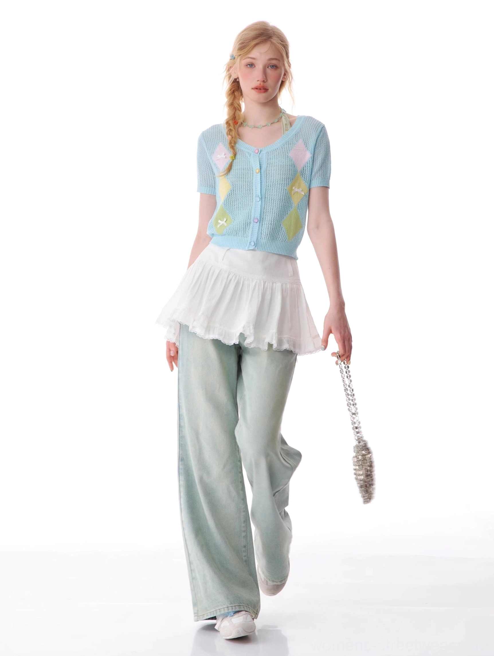 Women's light blue wide leg jeans styled with a cropped floral cardigan and silver chain handbag