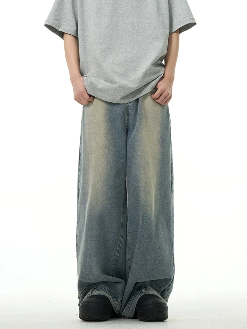 Rear-front view of light washed blue women’s wide-leg jeans with faded thigh details, oversized tee styling, layered cuffs, and relaxed Korean streetwear fit