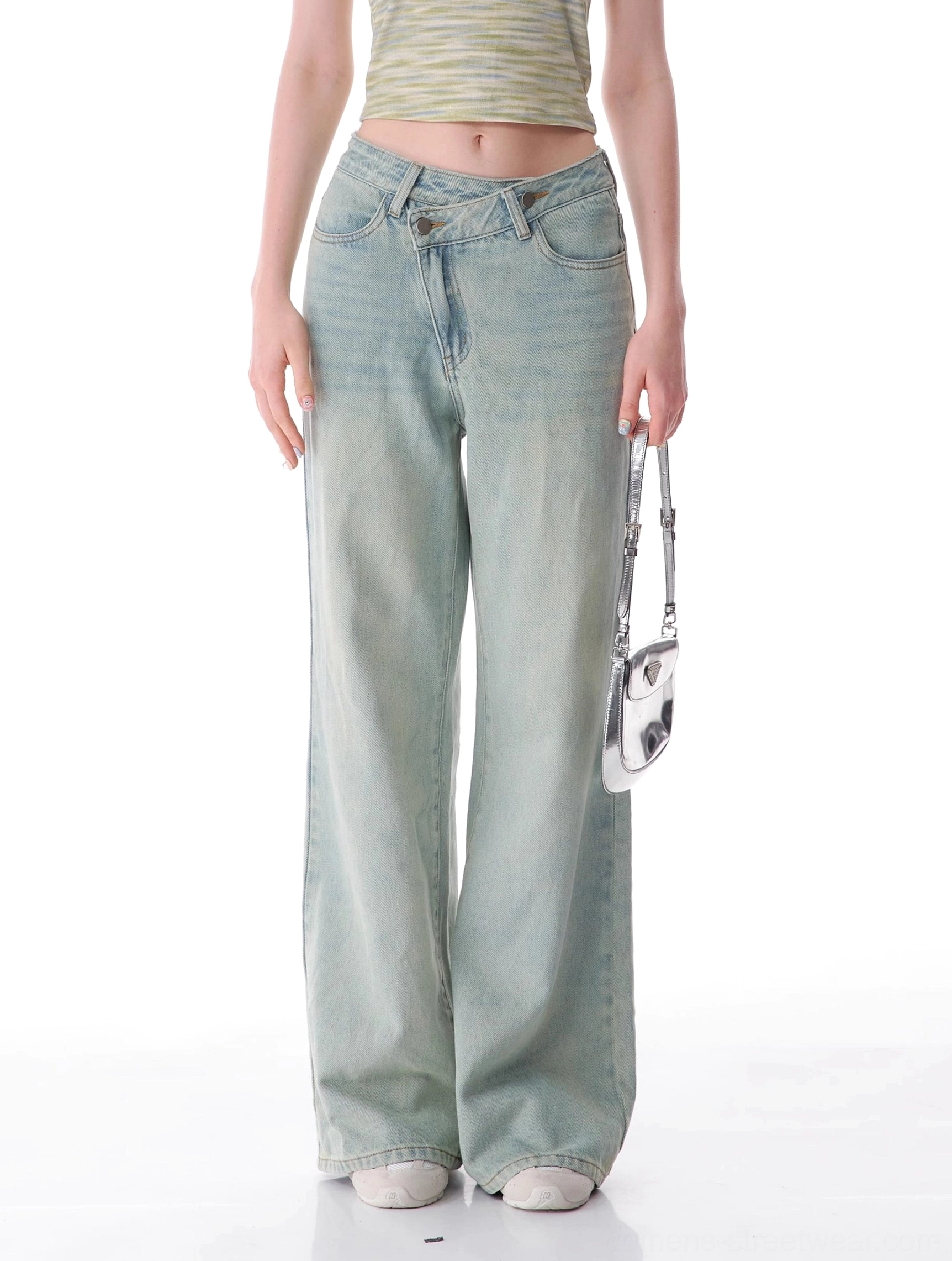 Women's light blue wide leg jeans styled with a cropped top and silver mini handbag in a modern streetwear outfit