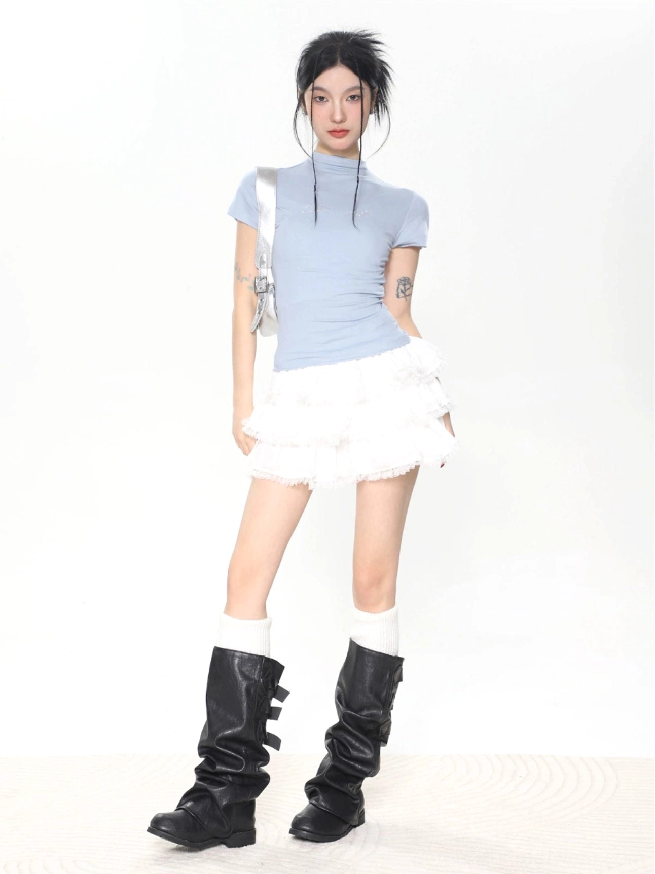Light blue women’s slim fit mock neck short sleeve baby tee styled with a white ruffle mini skirt and knee-high boots