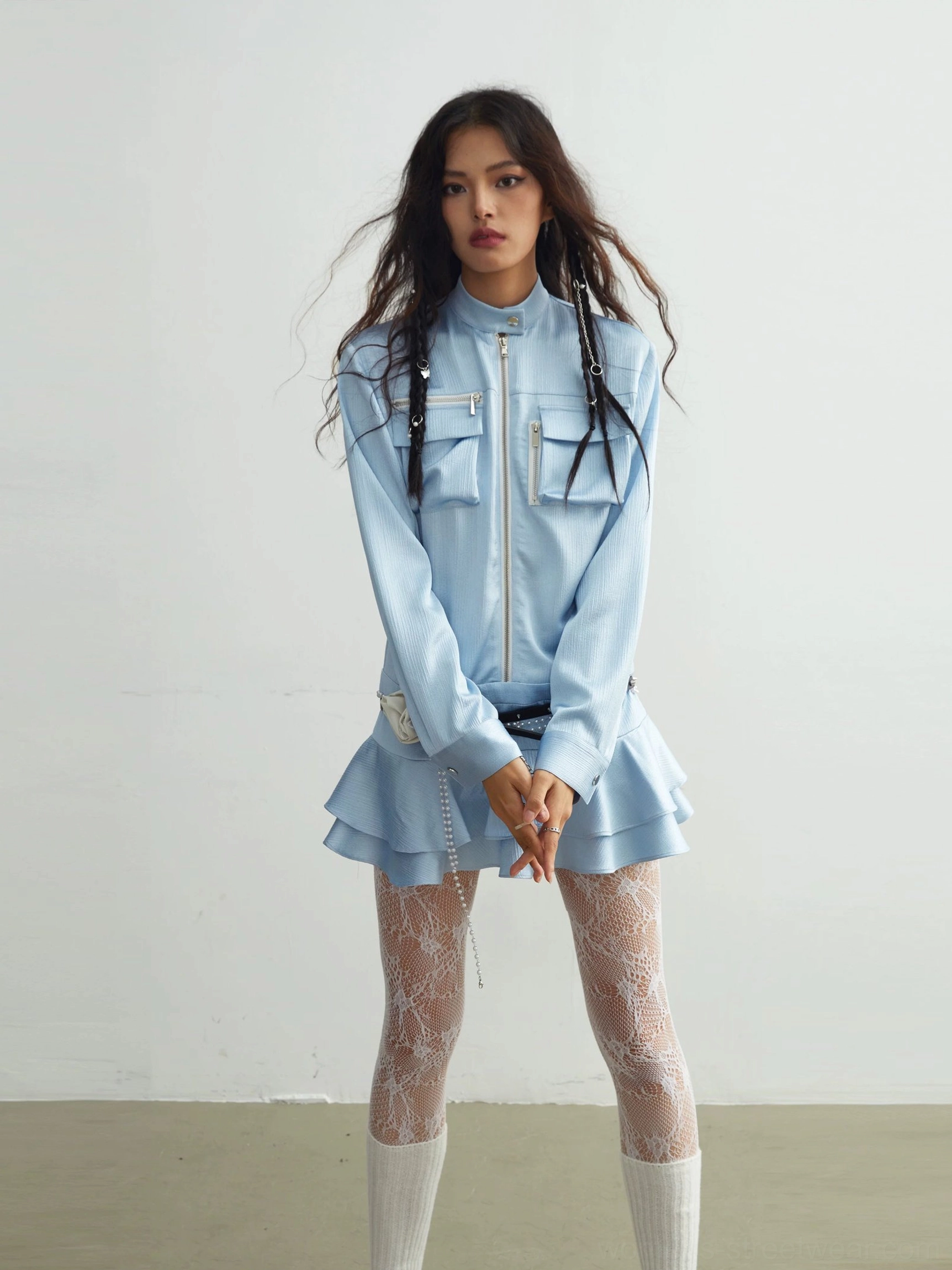 Front full-body view of light blue zip-up ruffle mini dress with stand collar, long sleeves, tiered hem, lace tights, and knee-high socks
