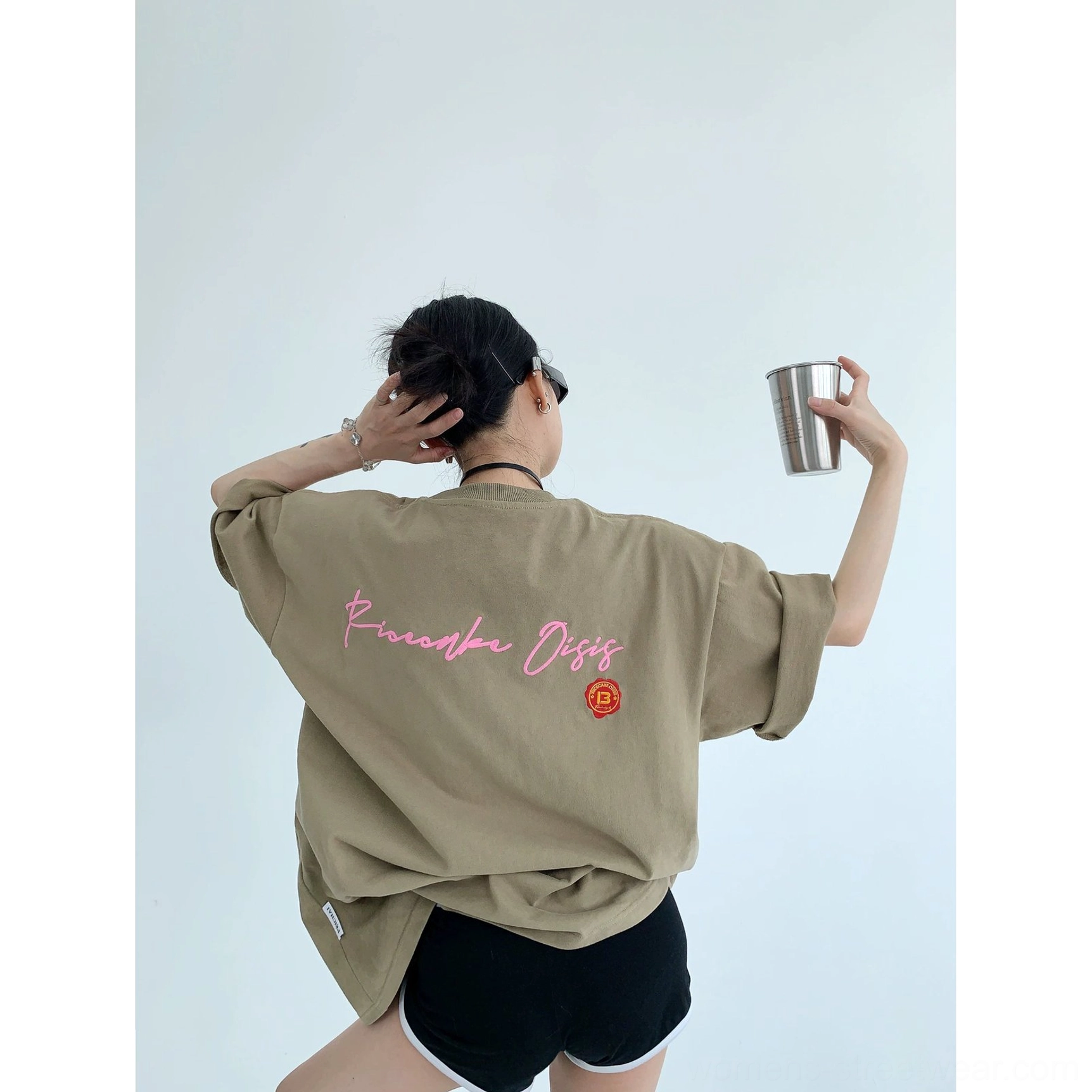 Light brown oversized neon script graphic cotton tee shown from the rear with pink lettering, rolled sleeves, and relaxed urban styling
