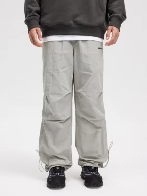 Light gray adjustable hem wide-leg streetwear track pants front view styled with cropped dark sweatshirt and black sneakers