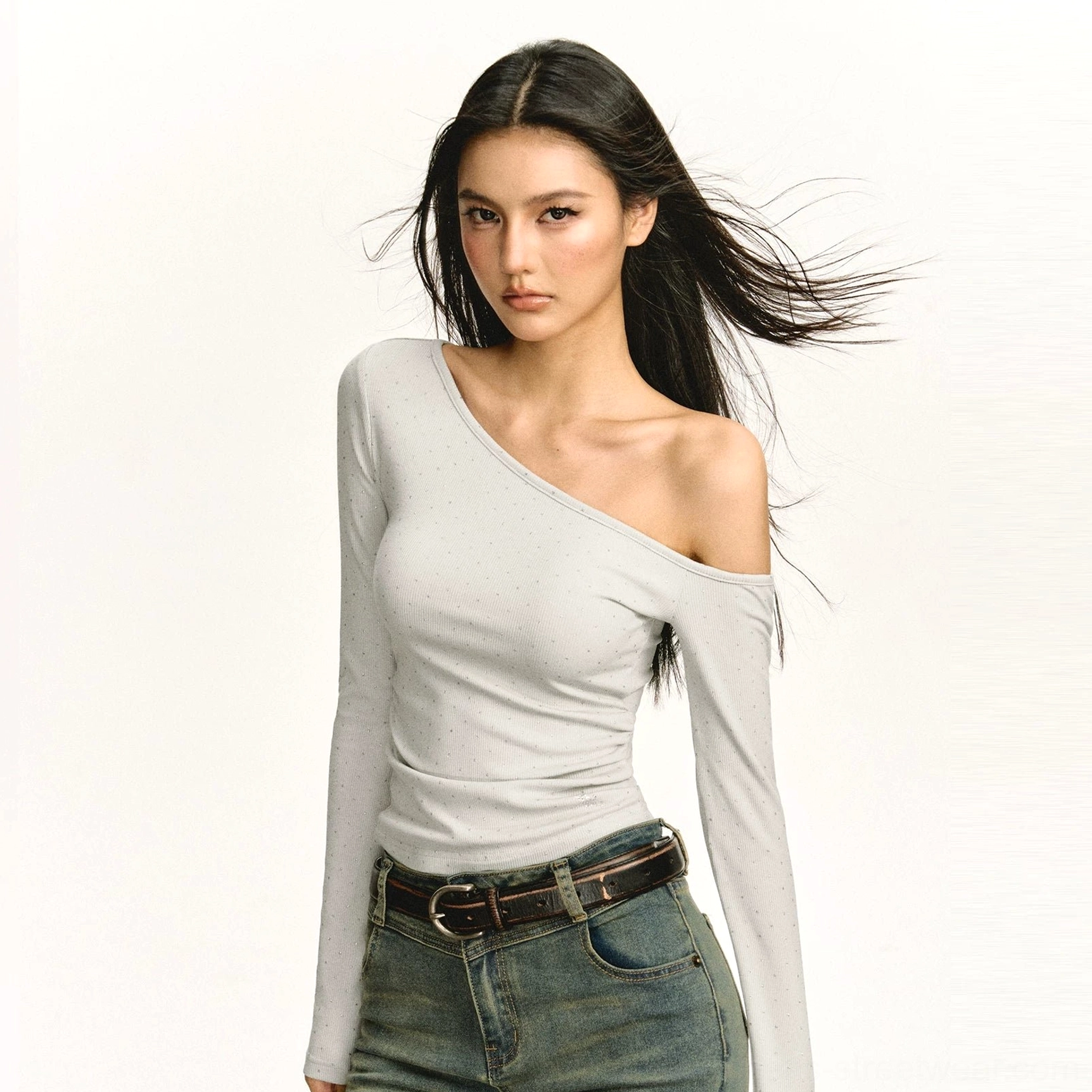 Light gray asymmetric off-shoulder ruched fitted long-sleeve top styled with vintage wash jeans