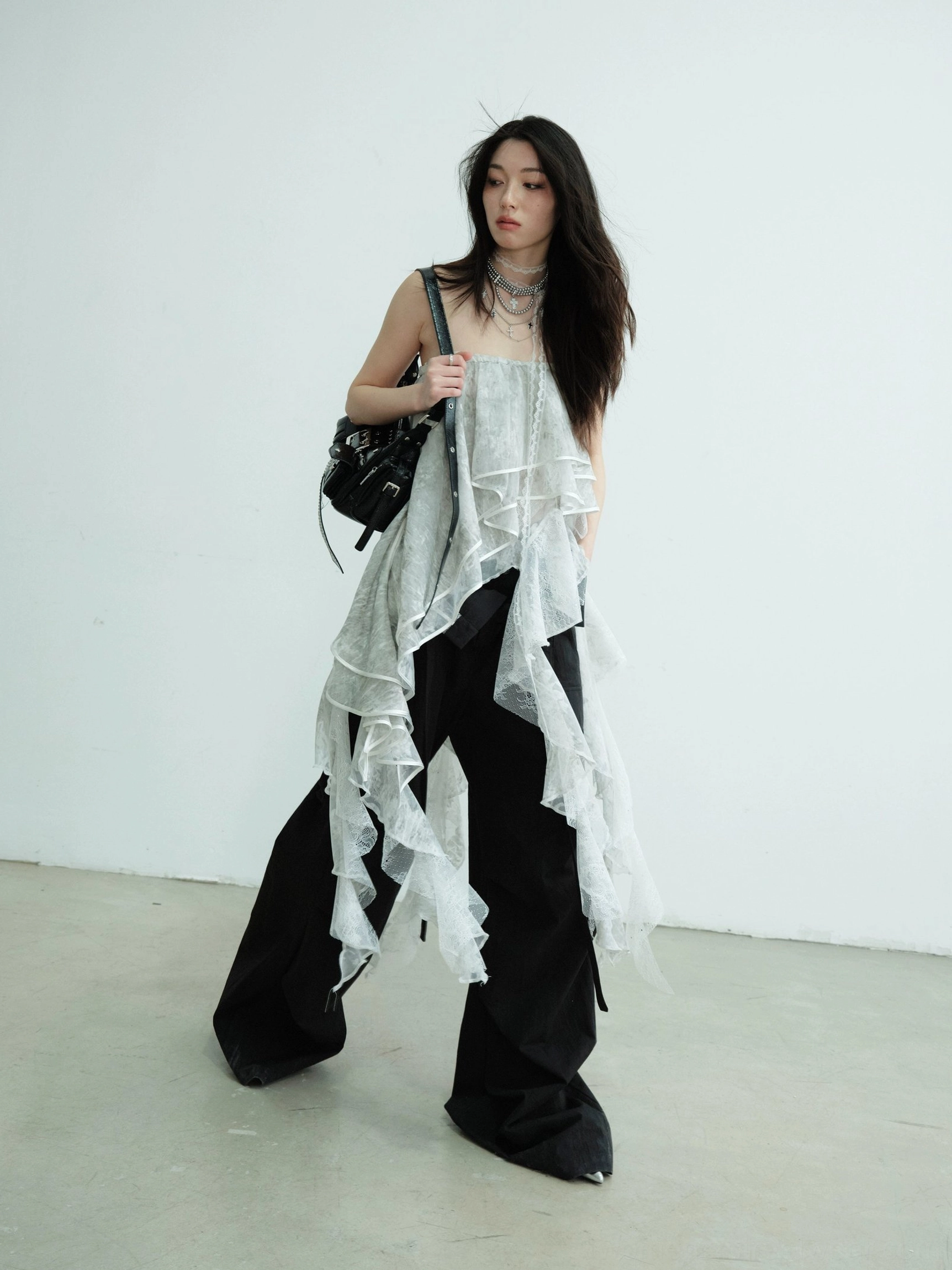 Light gray lace ruffle tube top maxi skirt in an asymmetric streetwear outfit with black wide leg trousers and shoulder bag