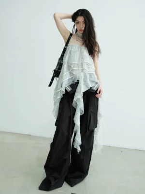Light gray convertible lace ruffle tube top maxi skirt styled as an asymmetric strapless top with black cargo pants in a white studio