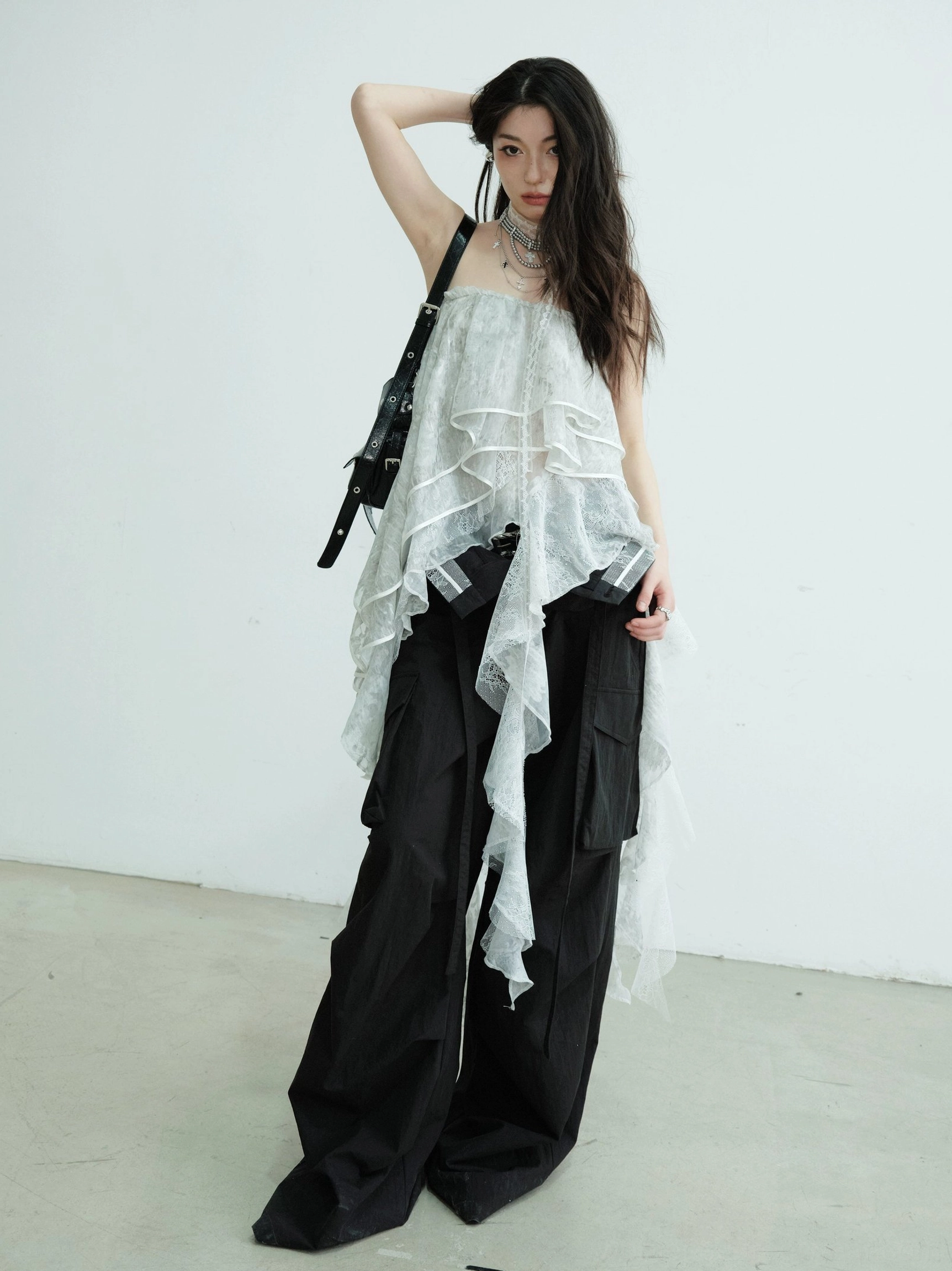 Light gray convertible lace ruffle tube top maxi skirt styled as an asymmetric strapless top with black cargo pants in a white studio